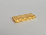 une barre d'or posée sur une surface blanche