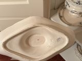 someone is holding a toilet bowl in their hand in front of a cabinet