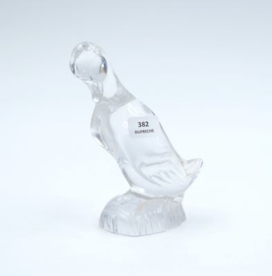 a clear glass duck sitting on top of a white table