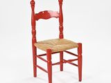 a red wooden chair with a wicker seat on a white background