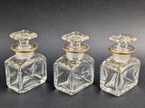 three clear glass bottles with gold trims on a black surface