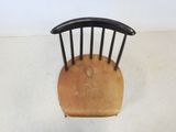 a small wooden chair with a black seat on a white floor