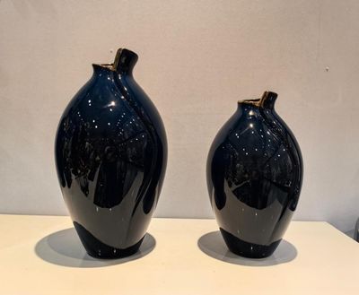 two black vases sitting on a white table