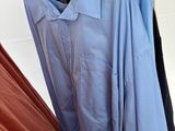 a blue shirt hanging on a hanger next to a pair of red pants