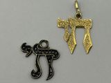 two gold and silver charms with hebrew symbols on them