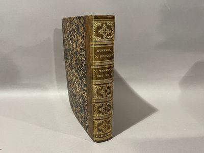 un vieux livre posé sur une table blanche à côté d'un mur blanc