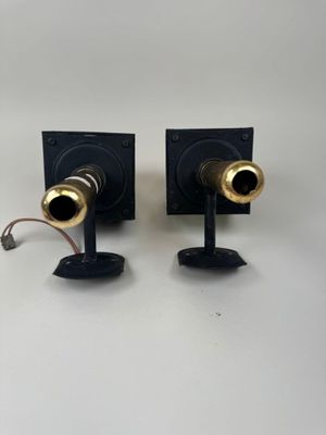 two black and gold speakers sitting on a white surface