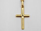 un pendentif en forme de croix en or, suspendu à une chaîne en or, sur fond blanc