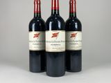 three bottles of red wine sitting on top of a white table