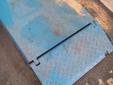 a blue piece of metal on the ground next to a trash can
