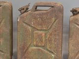 three old metal jerry cans sitting next to each other on a table