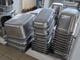 Plusieurs plateaux de nourriture sont empilés sur un chariot dans une cuisine