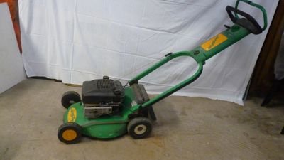 a green lawn mower that is sitting on the ground