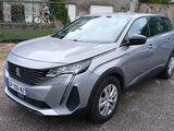 La voiture argentée est garée sur le parking devant la maison.