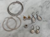 des bijoux en argent posés sur un plan de travail en marbre, à côté d'une paire de boucles d'oreilles et d'un collier