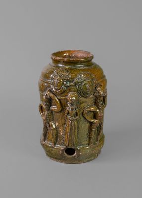 an old bronze vase with figures on it on a gray surface