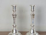 two silver candlesticks sitting on a wooden table