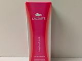 un flacon de parfum rose Lacoste posé sur une table