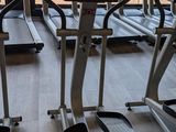 many tread machines in a gym room with a large window