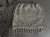 two silver and black beaded purses sitting on top of a table