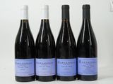 quatre bouteilles de vin sont alignées sur une surface blanche