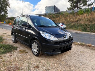 une photo d'une petite voiture noire garée sur le bord de la route