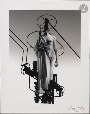photographie en noir et blanc d'une femme en robe, debout à côté d'une machine