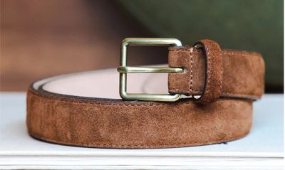 a brown belt with a metal buckle on a white table
