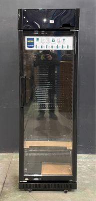 an image of a glass door refrigerator with a man standing in the background