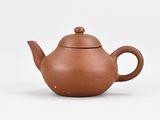 a small brown teapot sitting on a white surface