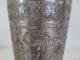 a silver cup sitting on top of a silver plate