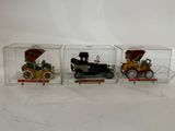 three toy cars are in a clear box on a white surface