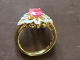 bague en or sertie d'une pierre rose entourée de diamants sur un fond noir