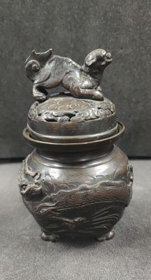 an image of a bronze urn with a dog on top of it