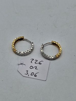 two gold and silver hoop earrings on a white surface