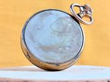 a silver pocket watch sitting on top of a tree stump