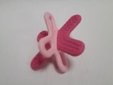 a pink pacifier on a white surface next to a pink object