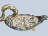 a picture of a ceramic duck shaped dish on a blue background