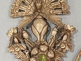 a gold brooch with a peacock on it next to a pair of rings