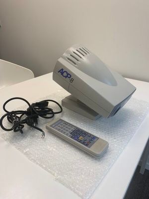 une table blanche sur laquelle se trouvent une télécommande et un ordinateur