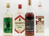 three bottles of gin are lined up on a white surface