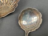 two silver spoons sitting on a table next to each other