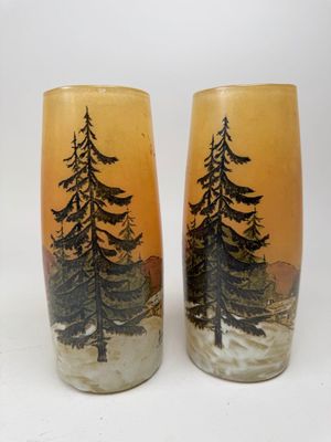 two tall vases with trees painted on them sitting on a table