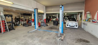 une voiture dans un garage où il y a beaucoup d'outils par terre