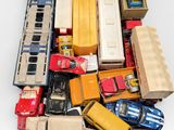un tas de petites voitures et de camions miniatures posés sur une surface blanche