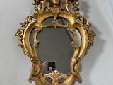 un miroir doré accroché au mur dans lequel on voit une femme