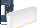 un appareil connecté blanc et jaune à côté d'un iPhone