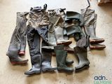 de nombreuses paires de bottes et de pantalons étalées par terre