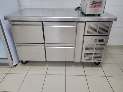 un comptoir en acier inoxydable équipé de deux réfrigérateurs et d'un congélateur