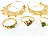 several gold rings and pendants on a white surface